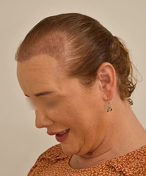 Woman with short hair smiling slightly downward.